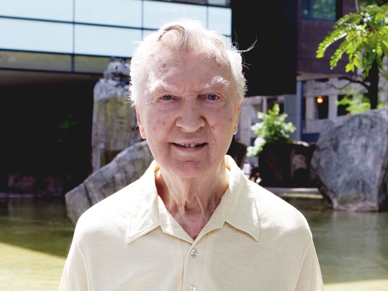 Retired Ryerson Professor Bill Strykowski, standing in front of the Devonian Pond on a sunny day