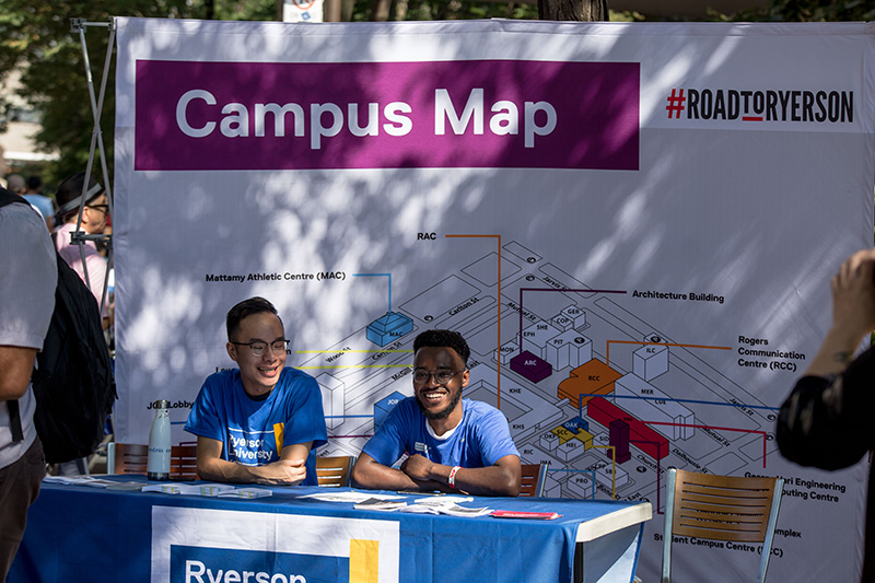 Two student volunteers during Welcome Week at a Campus Map booth on Gould Street