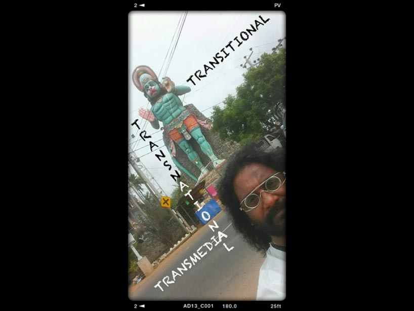 Cyrus Sundar Singh standing in front of large cultural statue: Transmedia, Transnational, Transitional