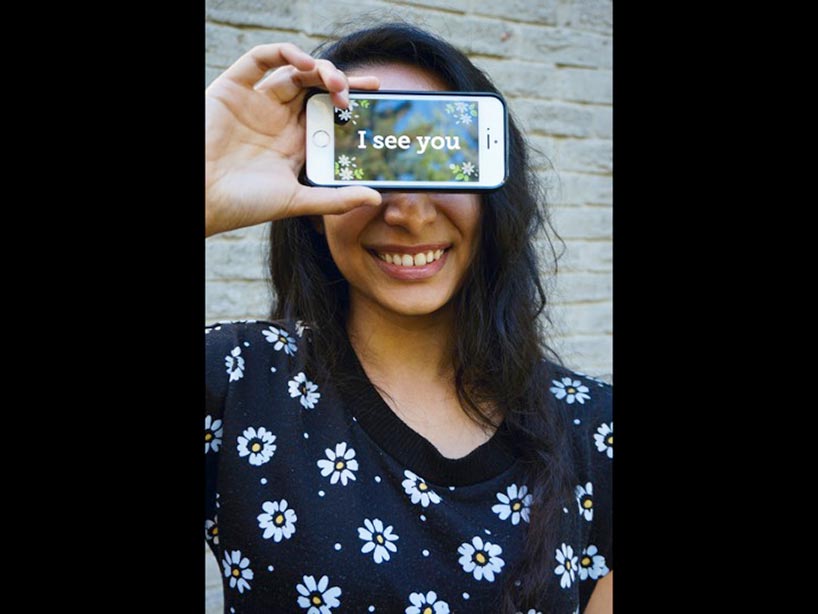 Natasha Ramoutar holding an IPhone across her eyes, the screen reads: "I see you"