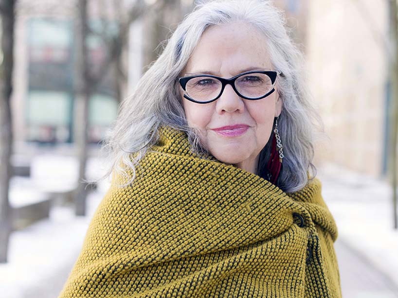 Woman with glasses, white hair and yellow shawl