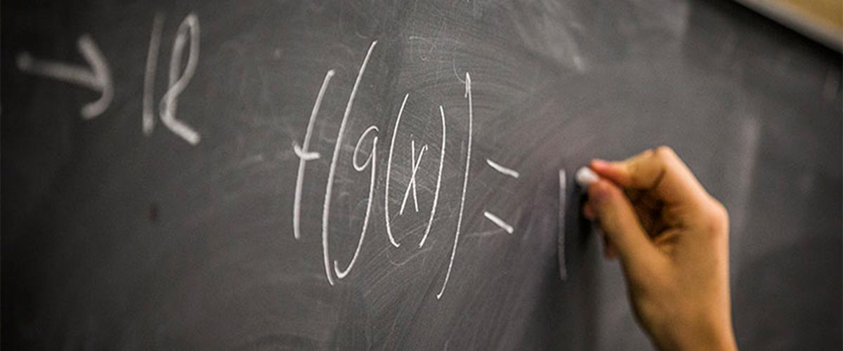 Graduate student writing a mathematical formula on chalkboard