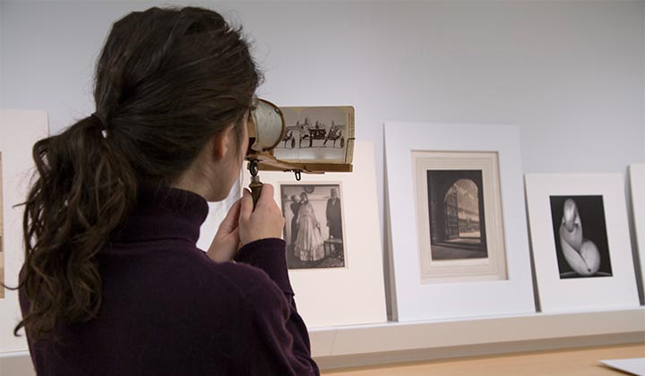 Student examining vintage photographs through a magnifying glass