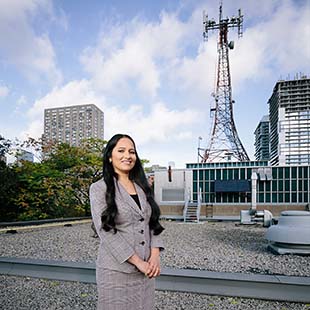 Female grad student on rooftop with cell tower