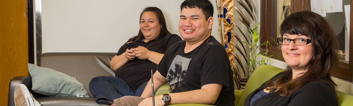 Three Indigenous people sitting smiling at the camera