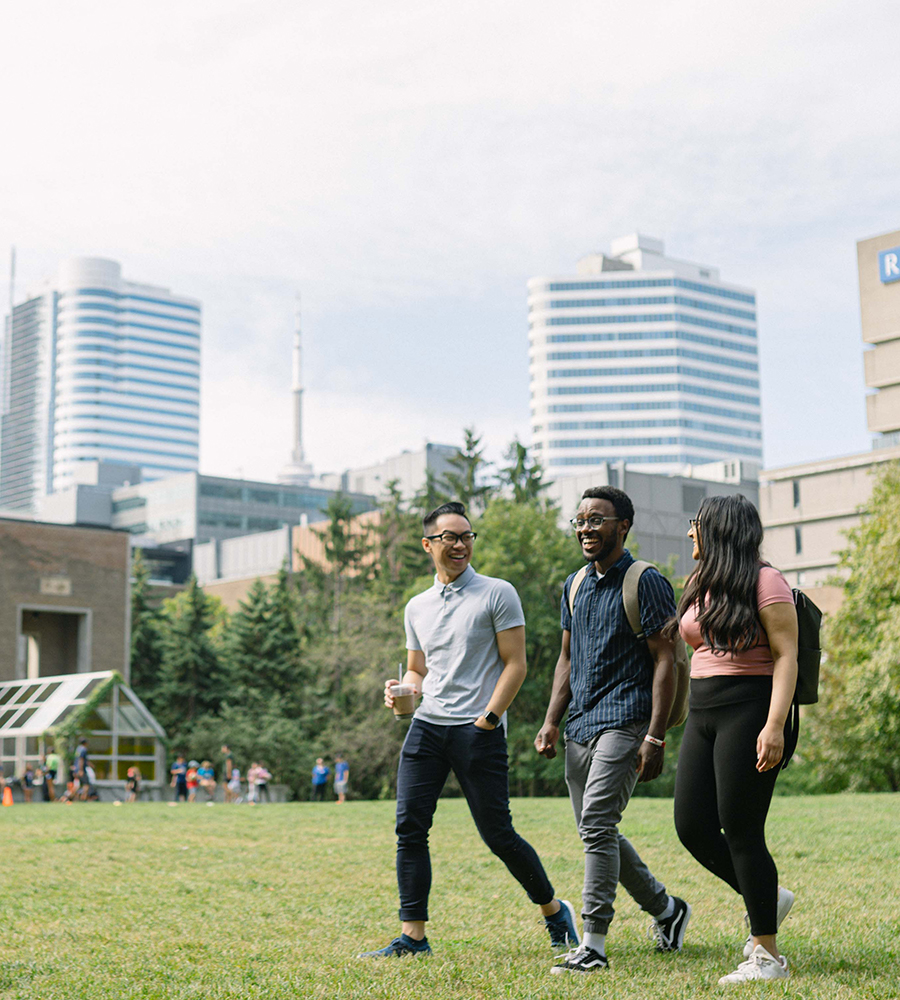 Three students walking in the Ryerson quad. Other students can be seen in the background.