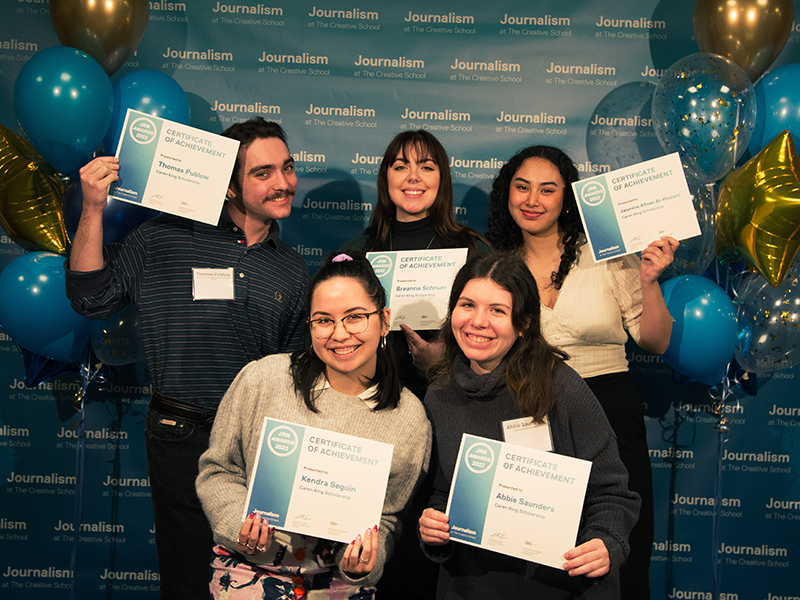 Abbie Saunders, Breanna Schnurr, Jasmine Afnan Al-Kholani, Kendra Seguin and Thomas Publow hold certificates while standing in front of a blue backdrop that repeats, "Journalism at The Creative School."