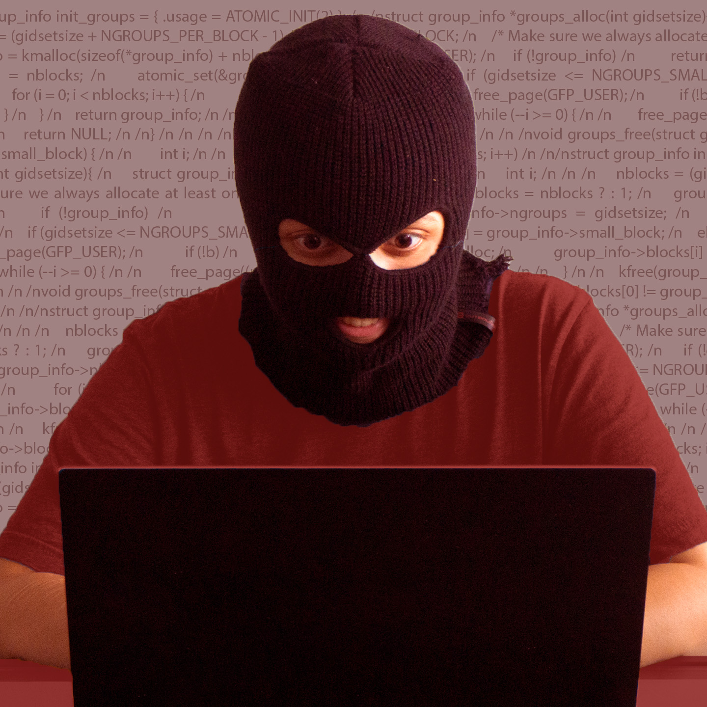 A student in a robber's mask at a laptop.