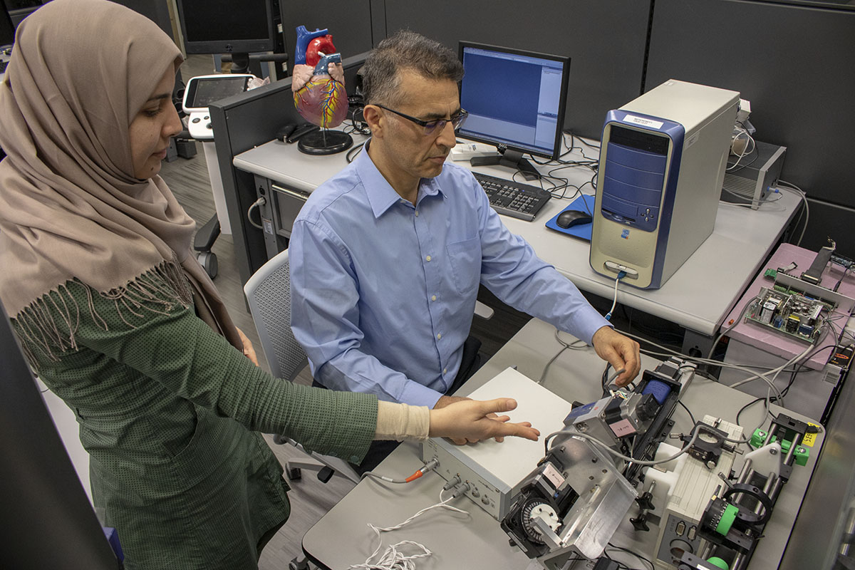 Farrokh Sharifi speaking with a student in a lab