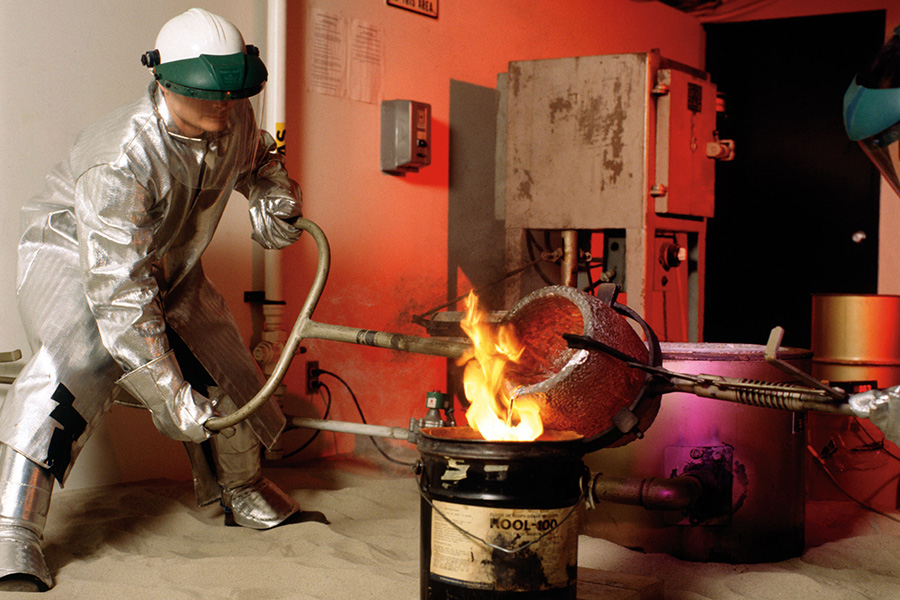A mechanical engineer pours metal over a fire in a lab