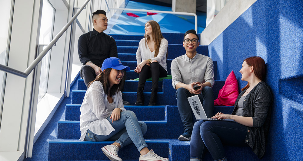 A group of students sitting on a staircase and chatting