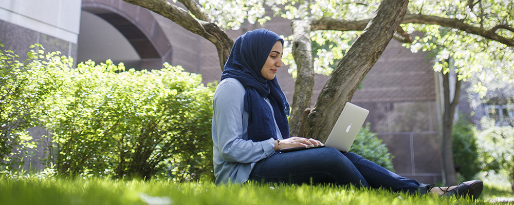 Female student sitting on the grass on campus