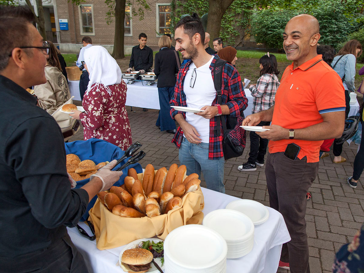 A man offering two people bread at a BBQ