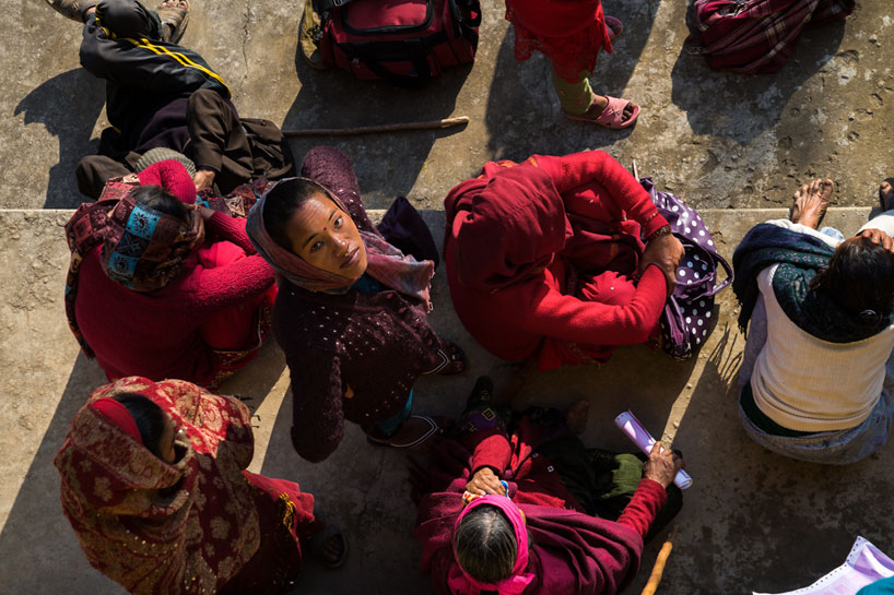 A queue of people waiting for medical treatment in Nepal, with one woman looking up to the camera