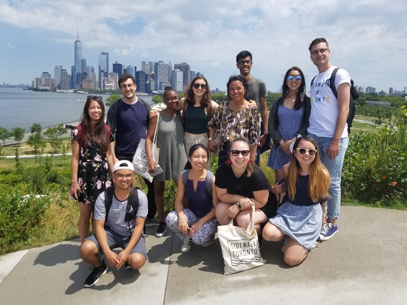 Young people posing on the waterfront with a cityscape behind them