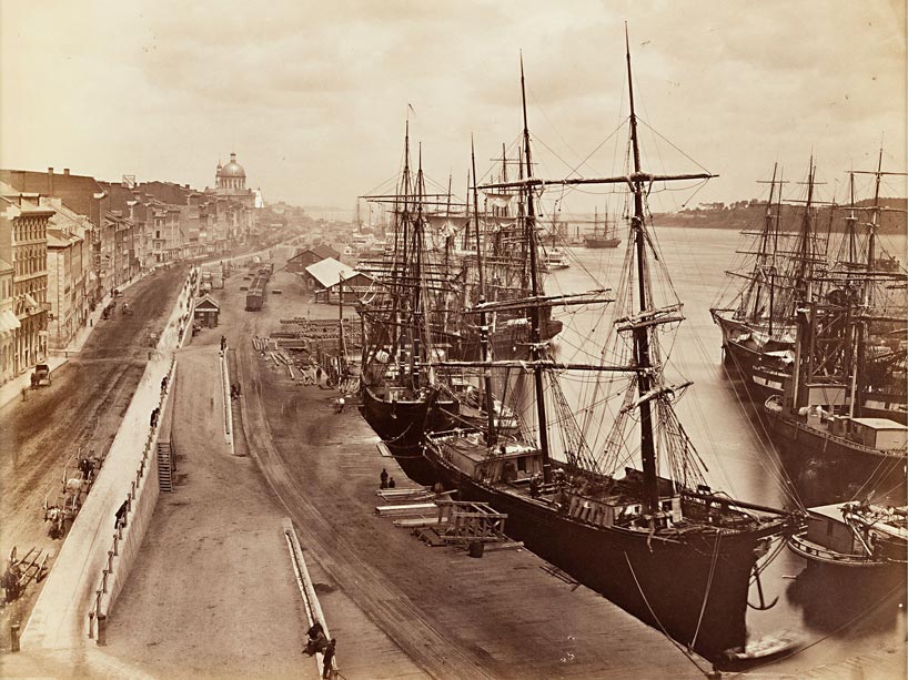 Black and white image of boats docked on the water in 19th century Quebec