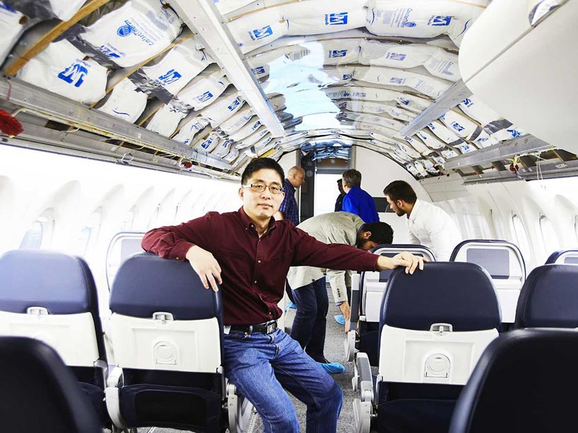 Fengfeng (Jeff) Xi in the airline cabin with researchers behind him testing ways to improve comfort on a plane