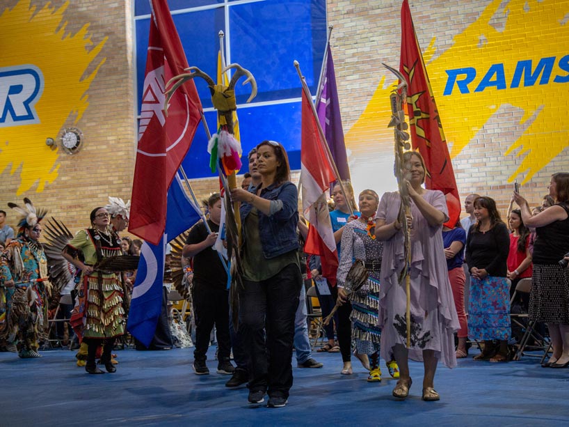 Hollee George carries the Two Spirit eagle staff (centre) and Monica McKay carries the Ryerson Eagle staff (right) during the Grand Entry at the Ryerson Pow Wow