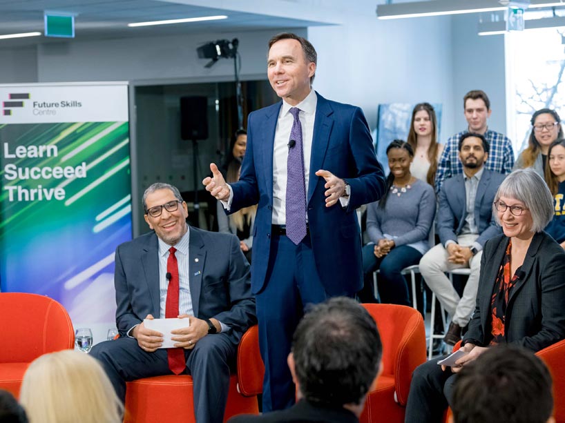 From left: Mohamed Lachemi sitting, Bill Morneau (centre) standing and Patty Hajdu sitting at the launch of the Future Skills Centre
