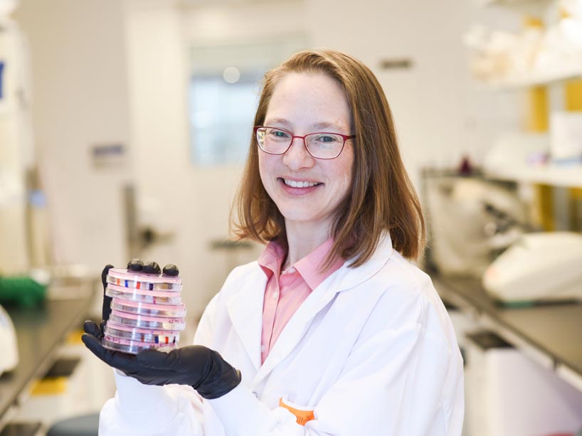 Woman researcher in the lab holding stack of petri dishes
