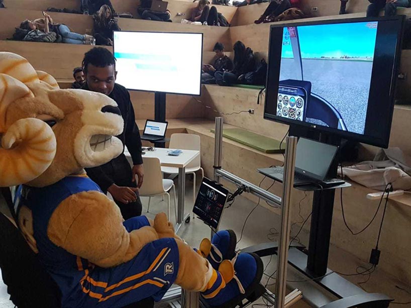 Eggy the Ram sitting in the driver seat of a simulated ride of a flying vehicle