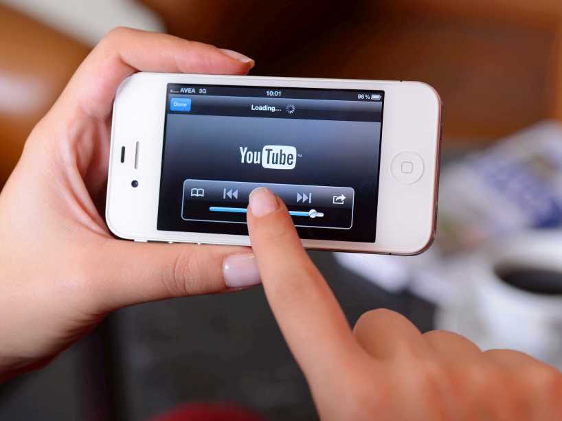 Two hands holding an iPhone that displays YouTube.