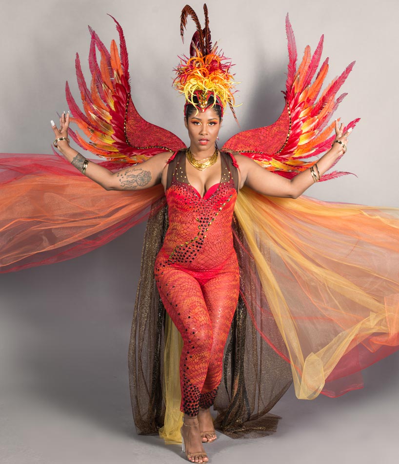 a woman wearing a colourful costume resembling a phoenix posing with her arms outstretched