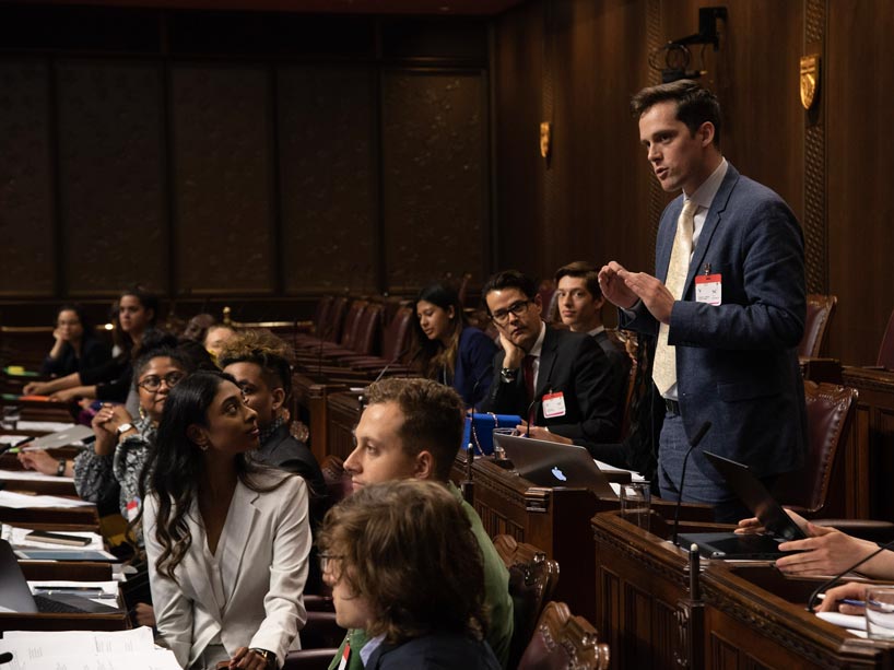 In the Parliament’s Senate chambers, Matthew Chisolm stands and speaks as other students, seated, listen