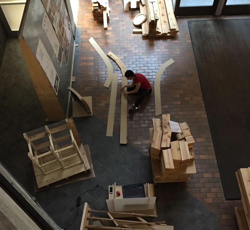 Student working on wooden pieces on the floor of the architectural science building