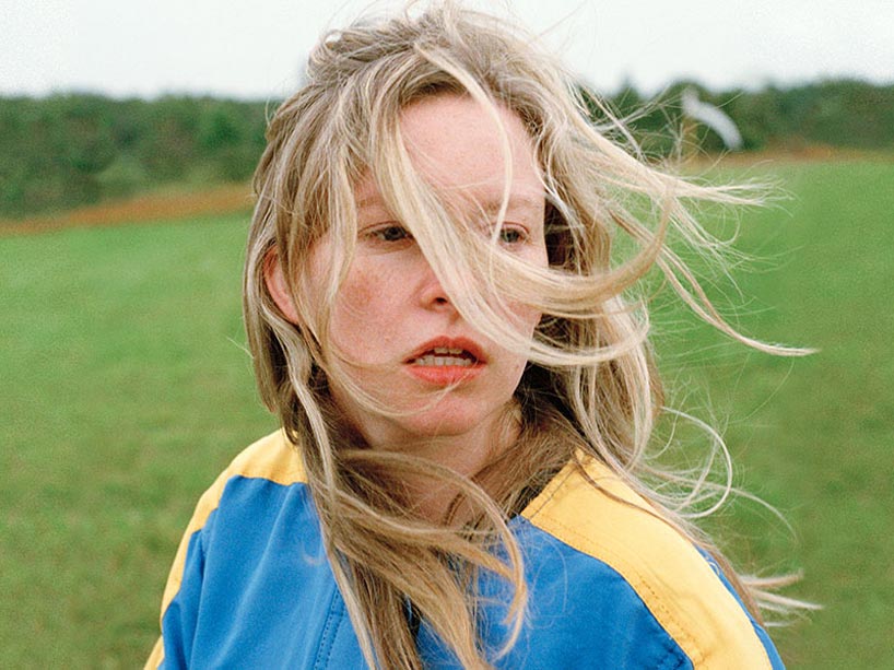 Woman standing in a field with windblown hair on her face
