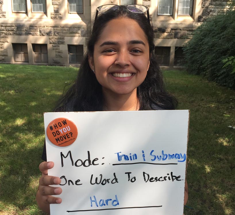 Student holds a sign that says the hardest part of her commute is that it’s hard