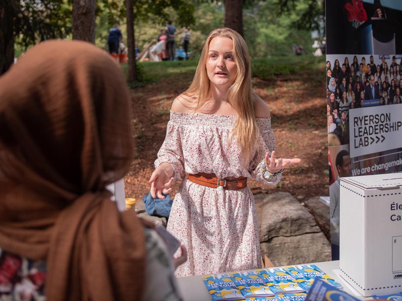 A student speaks to another student at a booth on the campus about the importance of voting in the upcoming federal election.