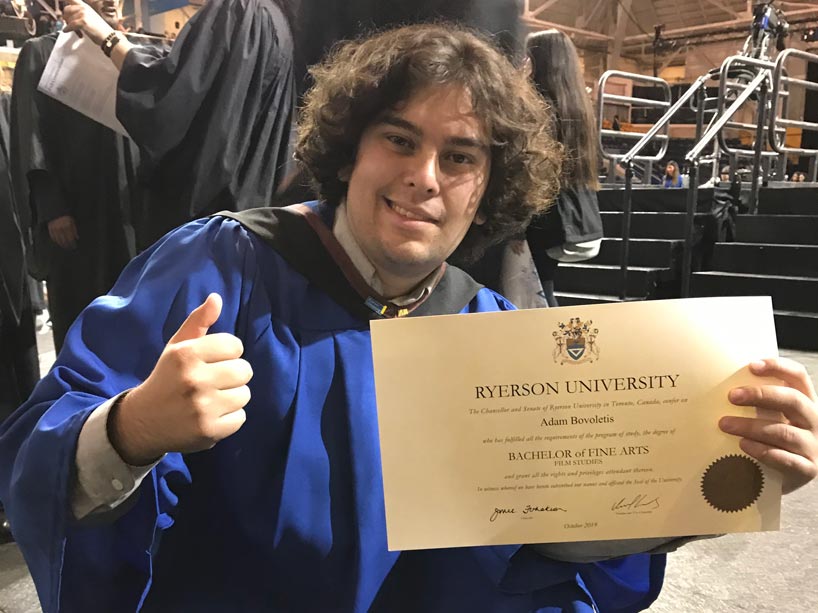 Adam Bovoletis gives a thumbs up while holding his degree on the day of his convocation 