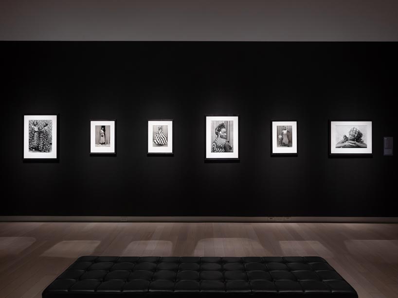 Framed black and white photos on a black wall in an exhibition hall