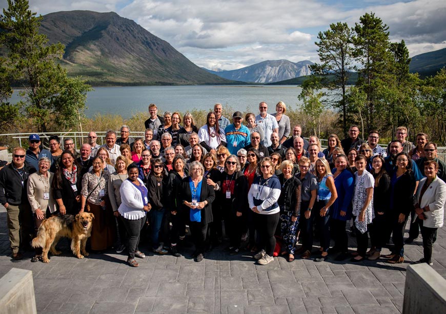 Group shot of university leaders with mountains and a body of water in the background