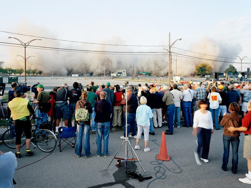 A crowd of people watching a building go up in smoke