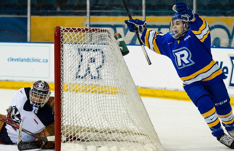 A female hockey player skates around the back of the net with her arms up in celebration