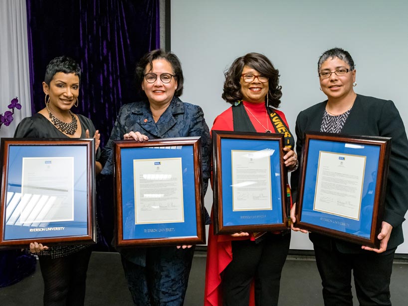 Four women holding award plaques