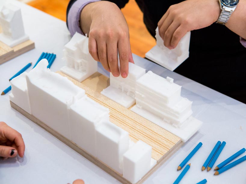 Two players playing a board game with 3D printed building models.