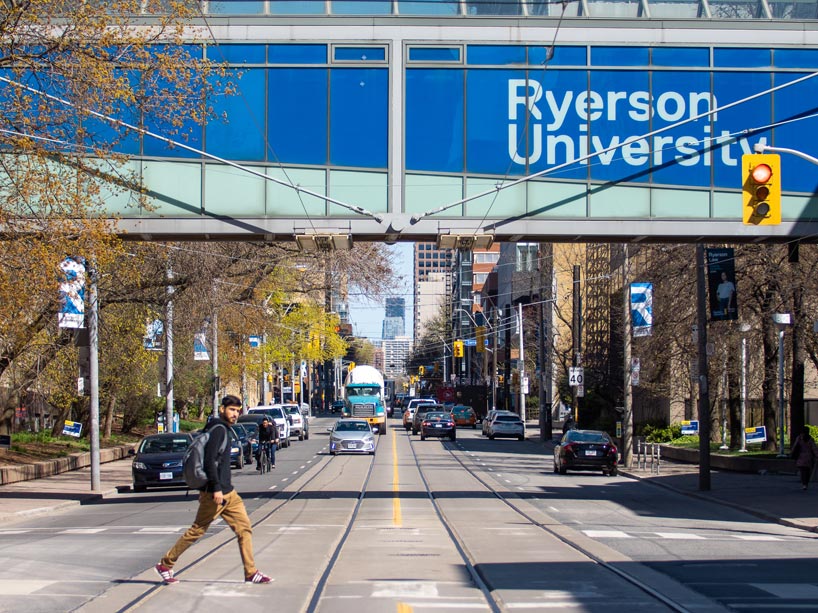 A student walking across an intersection in front of a Ryerson building