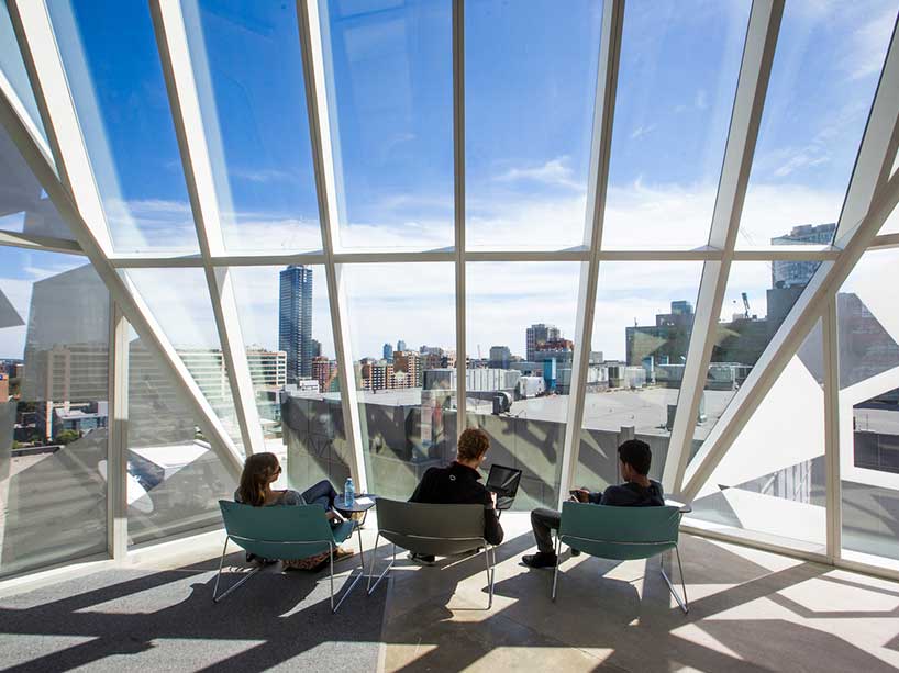 A rendering of three people sitting on chairs looking out a window overlooking campus