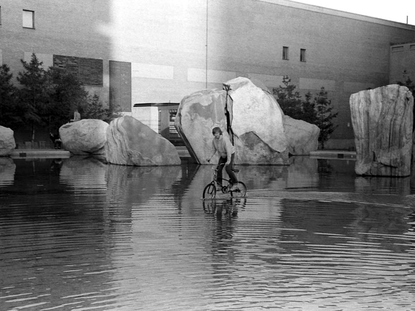 A young man rides a bicycle through Lake Devo on Ryerson’s campus