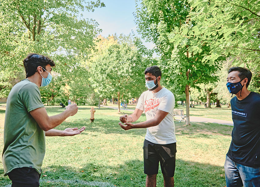 Students playing games with masks on in a park