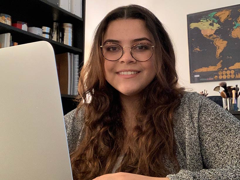 International student Monica Salloum at her home desk working on a laptop