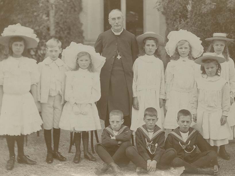 School-aged children standing with a bishop for a photo.