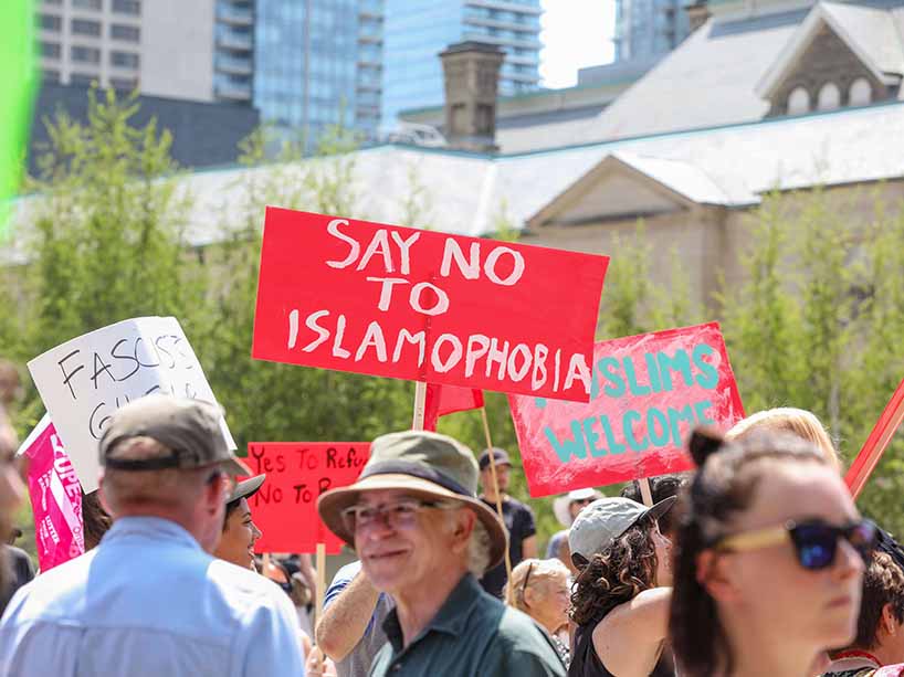 Protestors hold placards, with one pointing toward the camera that says ‘Say no to Islamophobia.