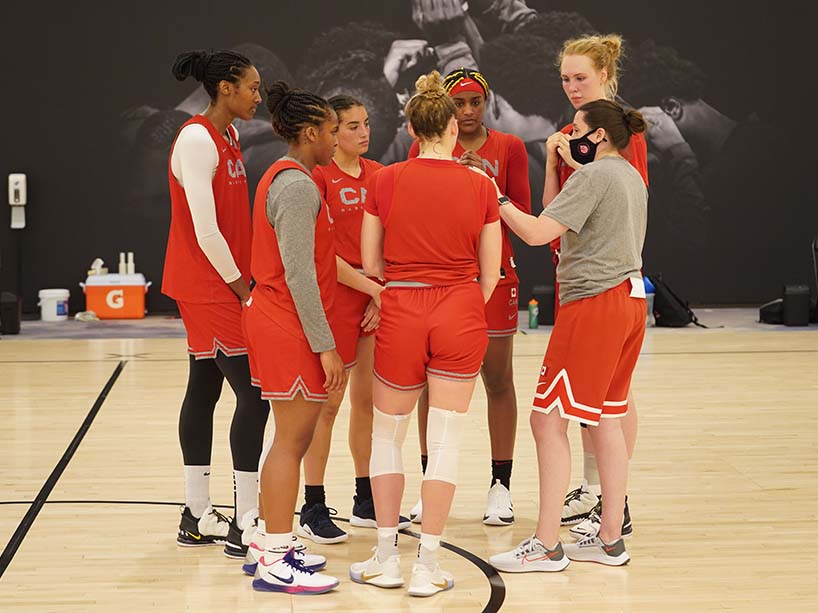 A team of basketball players on the court in a huddle.