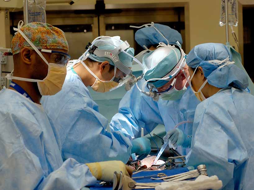 A group of medical students gather around for surgery.