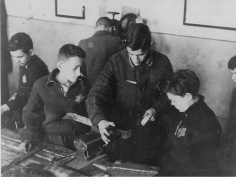 A young man showing a group of children how to operate a machine.