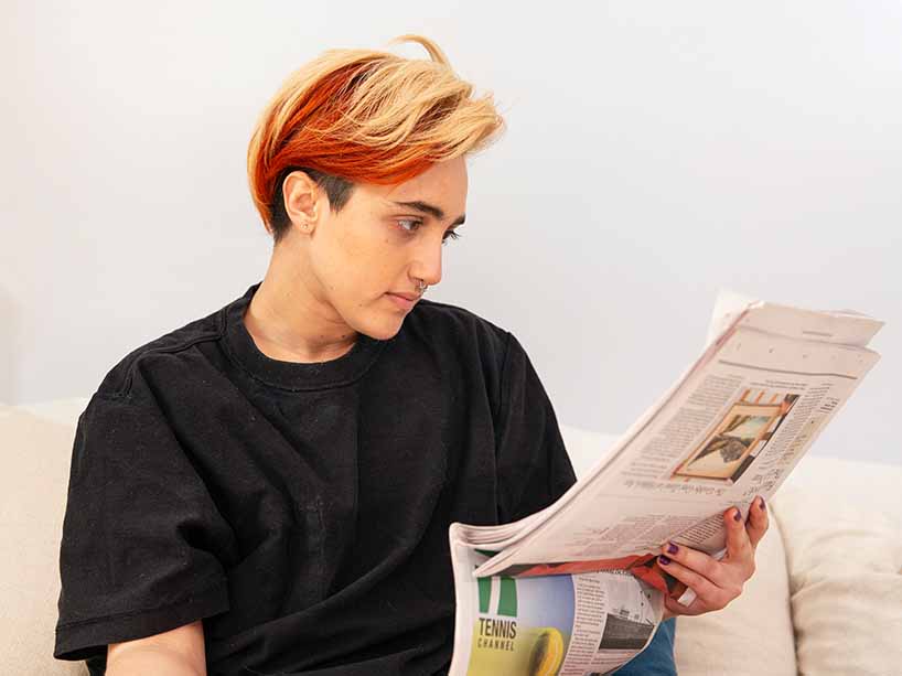  A transmasculine gender non-conforming person reading a newspaper.